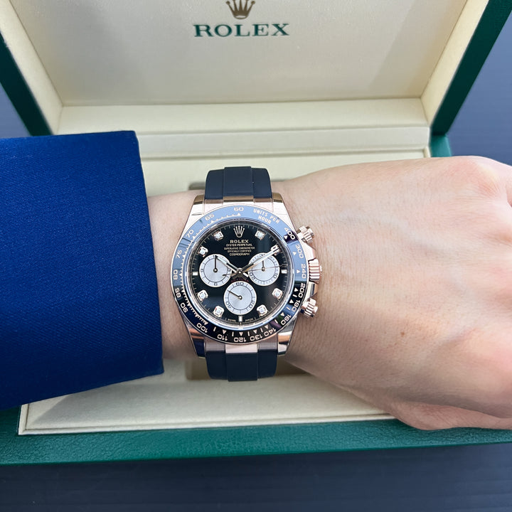 Rolex watch on a wrist with a blue sleeve and green box in the background
