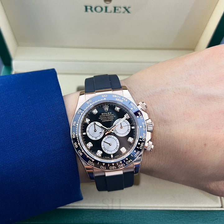 Rolex watch on a person's wrist with a blue strap, displayed against a Rolex box.