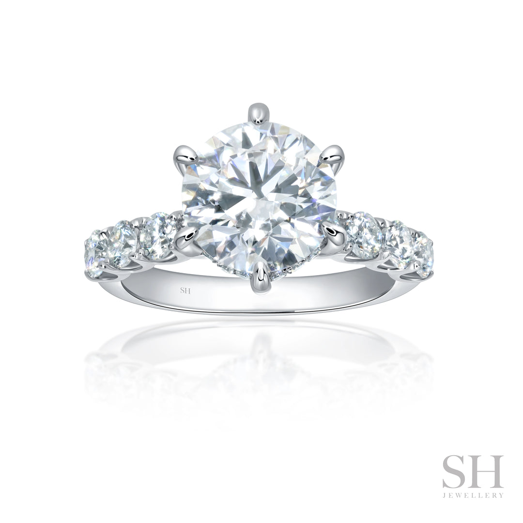 An 18kt white gold engagement ring featuring a brilliant cut diamond with a scalloped band and hidden halo.