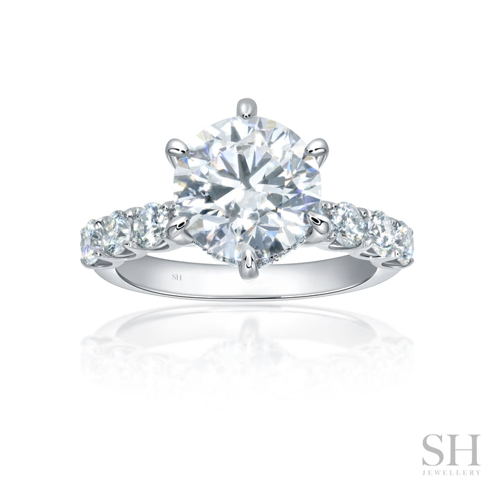 An 18kt white gold engagement ring featuring a brilliant cut diamond with a scalloped band and hidden halo.