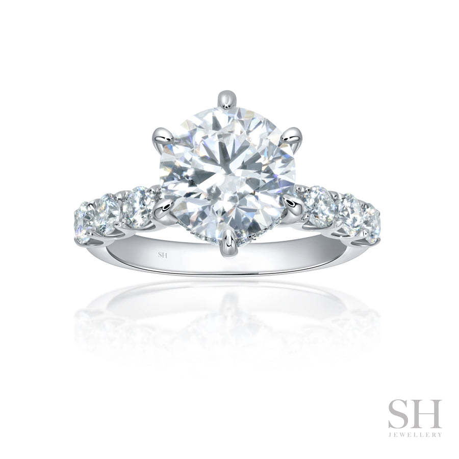 An 18kt white gold engagement ring featuring a brilliant cut diamond with a scalloped band and hidden halo.