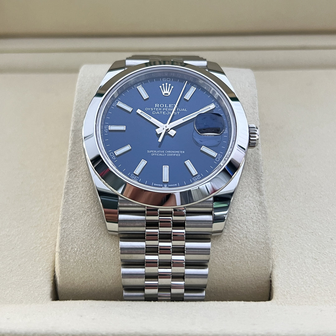 Silver watch with blue dial on a beige cushion