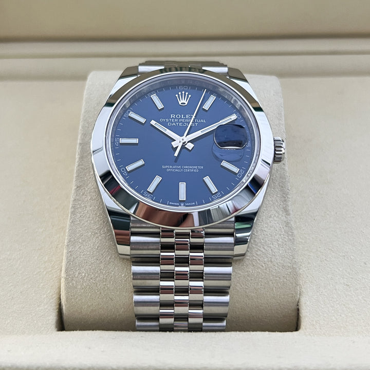 Silver watch with blue dial on a beige cushion