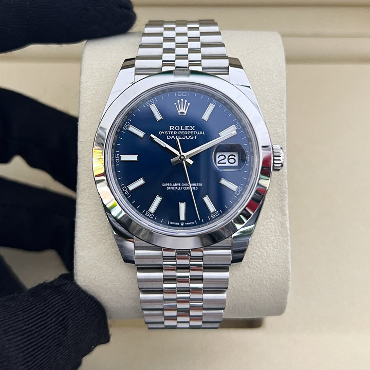 Silver watch with blue dial on a beige cushion