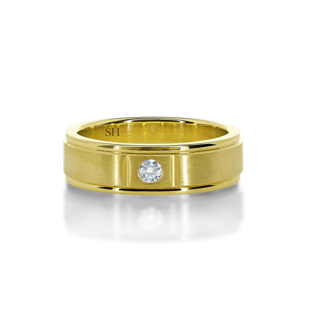 Men's satin finish diamond wedding band with grooves to edges R12-002B-W0074. This classic 18k white gold men's wedding band has been centrally hammer set with a round brilliant cut diamond. The subtlety of the diamond is enhanced with an all over satin finish. The ring has an extra thickness and weight to it and has a uniform width. Although the profile of this ring is flat